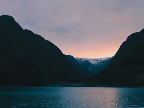 Fjord i solnedgang med fjell på begge sider